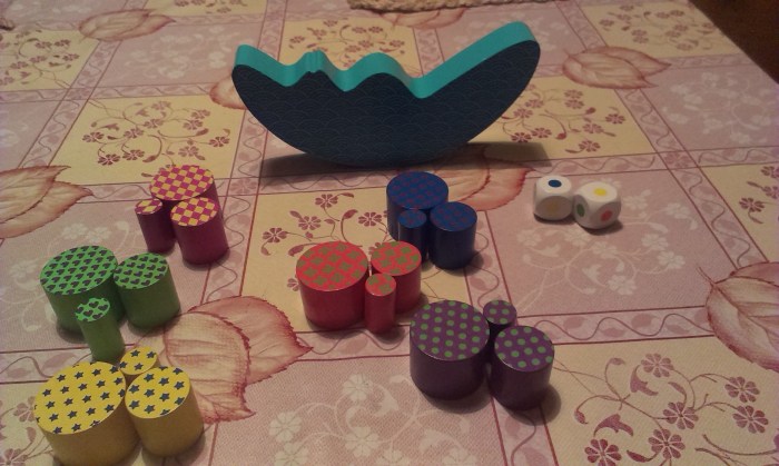 The contents of the box - One "Tipping Moon", 6 different color sets each with three circular pieces of different sizes and two dice with each of the colors shown on each of its sides.